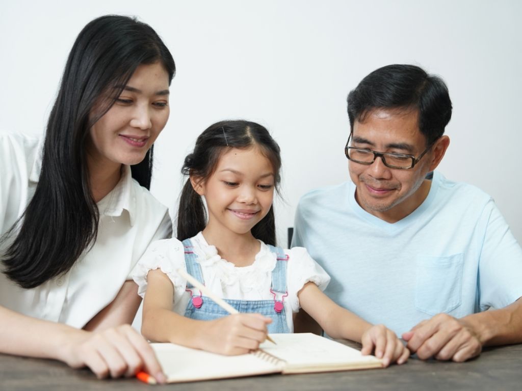 Mom and dad teaching their young daughter at home, demonstrating how to teach and educate kids in a home environment.